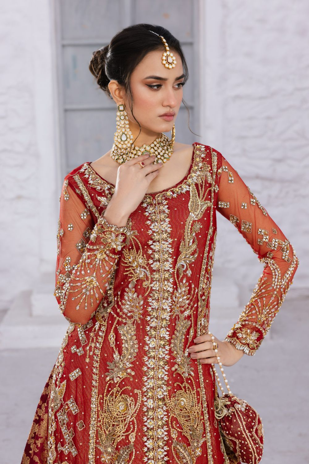 Close-up of red heavily embroidered formal dress with sheer embellished sleeves and intricate gold beadwork